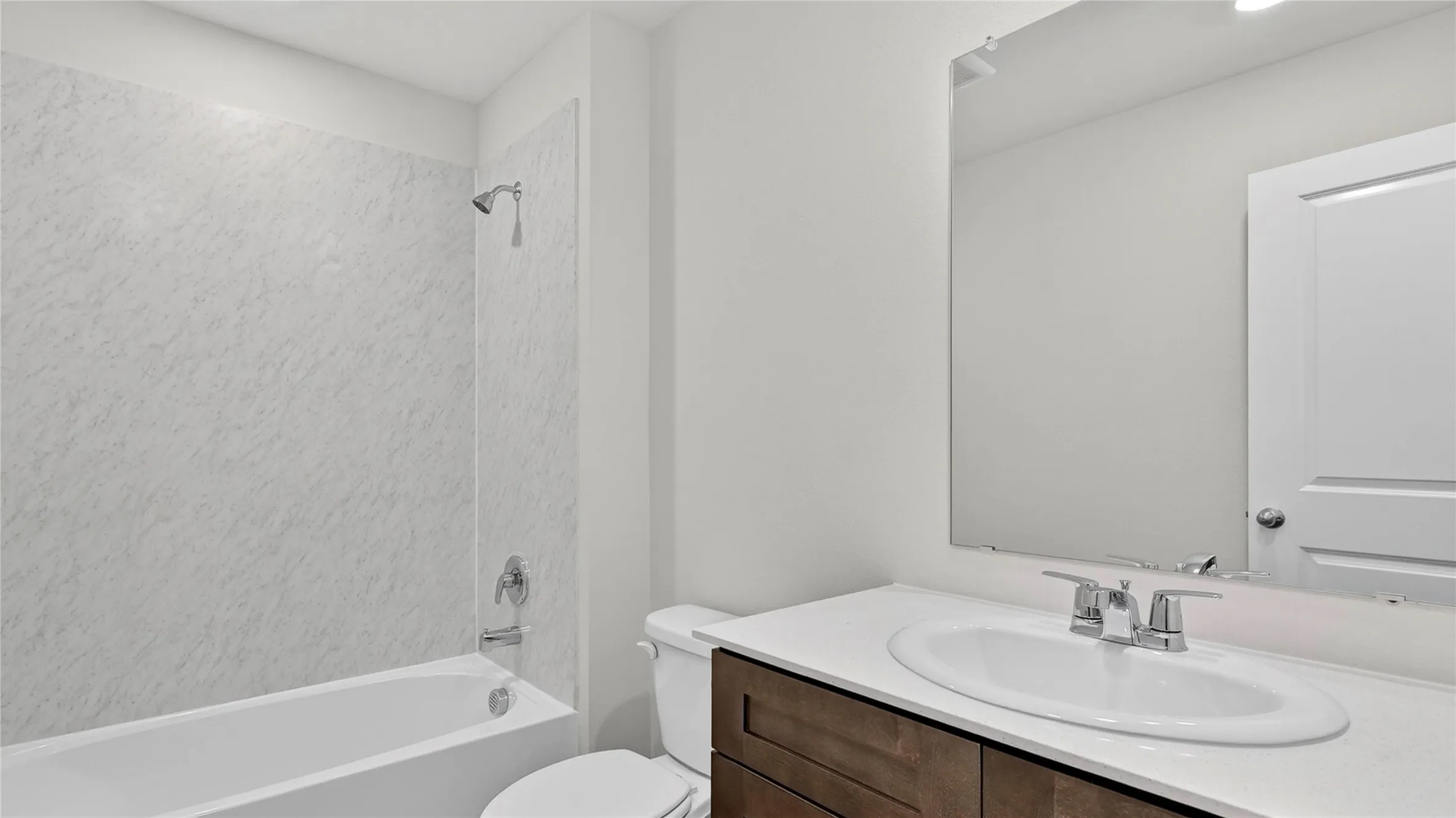 Bathroom featuring a white bathtub, chrome shower fixtures, and a vanity with a white countertop and oval sink