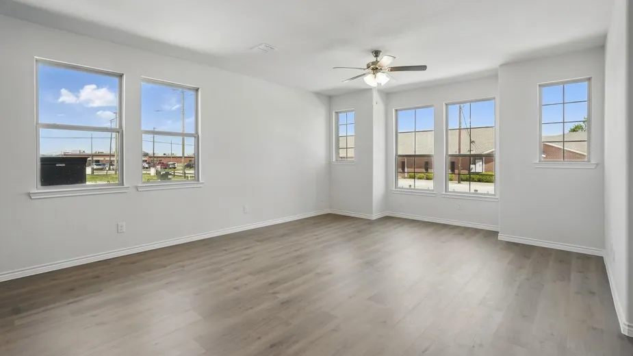 Spacious interior featuring light wood-finish flooring, white baseboards, and a neutral wall color