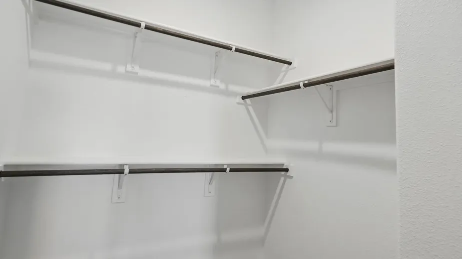 White-painted closet featuring multiple shelving units and dark-finish hanging rods