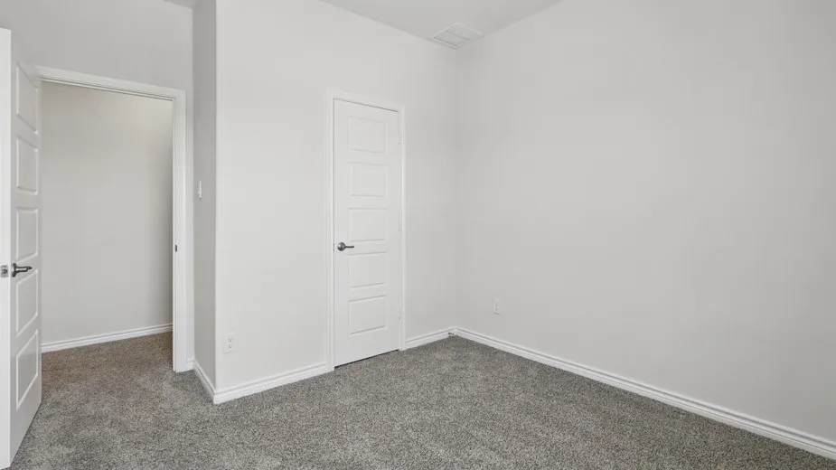 Neutral-toned interior room featuring light gray carpeting and white baseboards