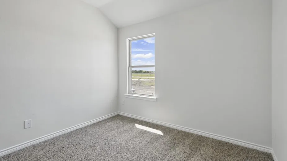 Bright room featuring a single window, vaulted ceiling, light gray textured walls, and gray carpet flooring with white baseboards