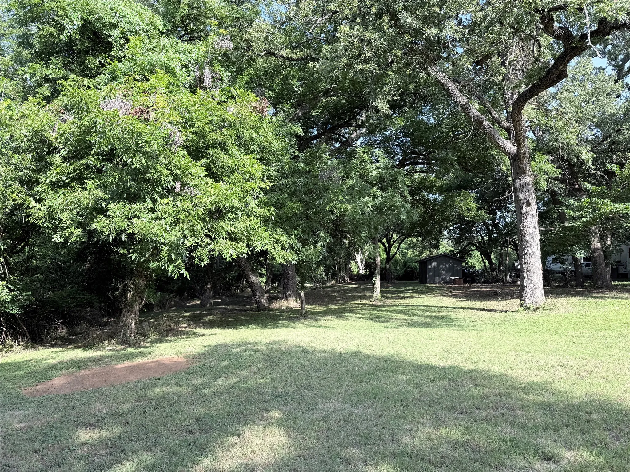 Expansive outdoor space featuring a lush green lawn and mature trees