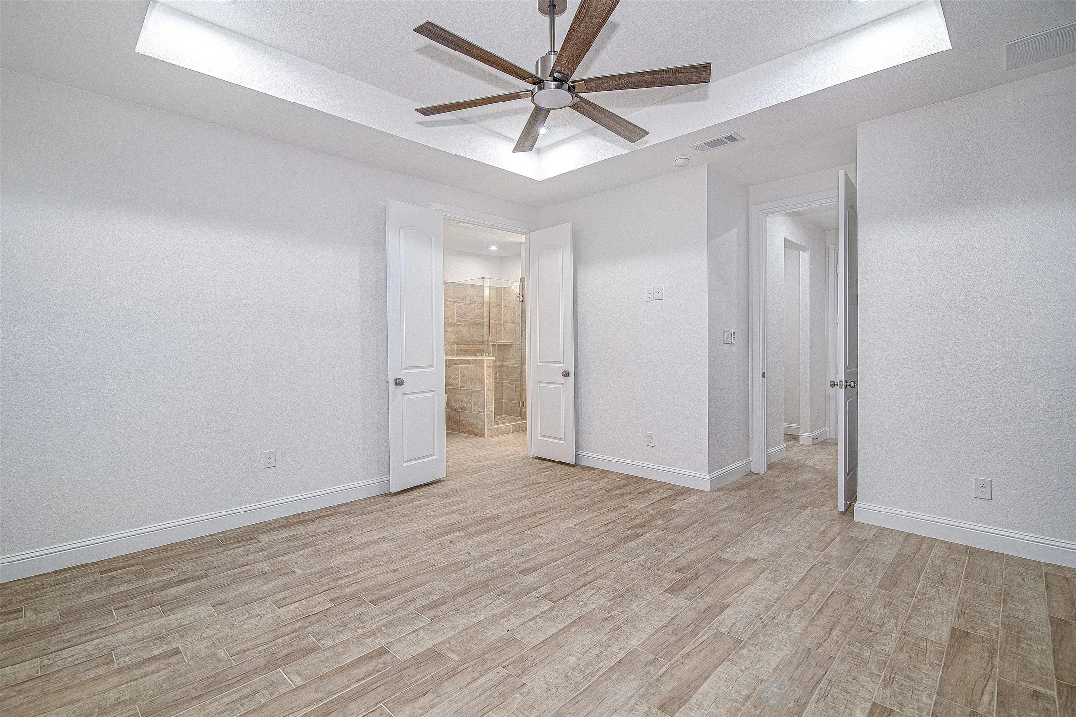 Unfurnished bedroom featuring light wood-type flooring, a raised ceiling, and baseboards