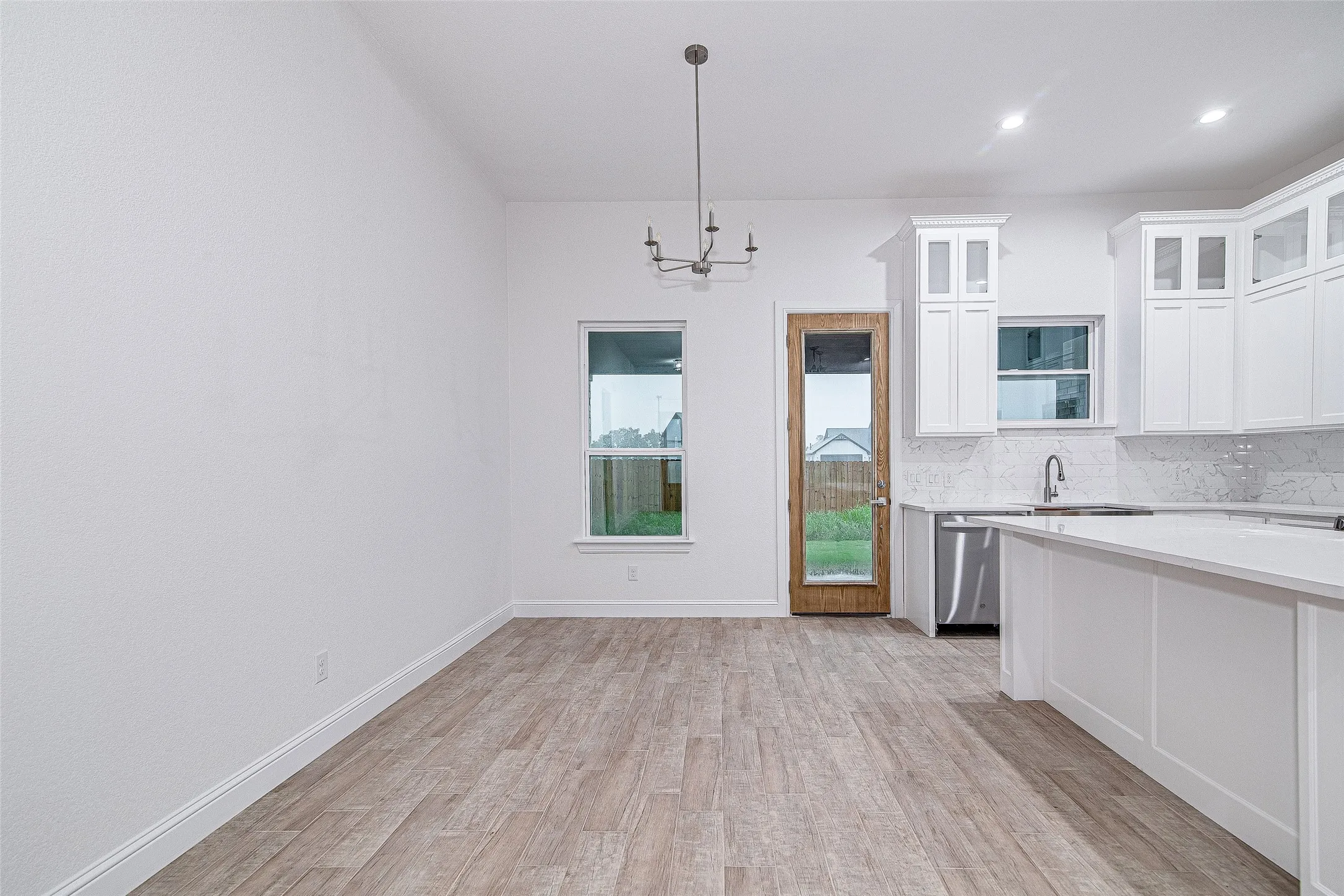 Kitchen featuring a chandelier, light countertops, light wood-style flooring, tasteful backsplash, and white cabinetry