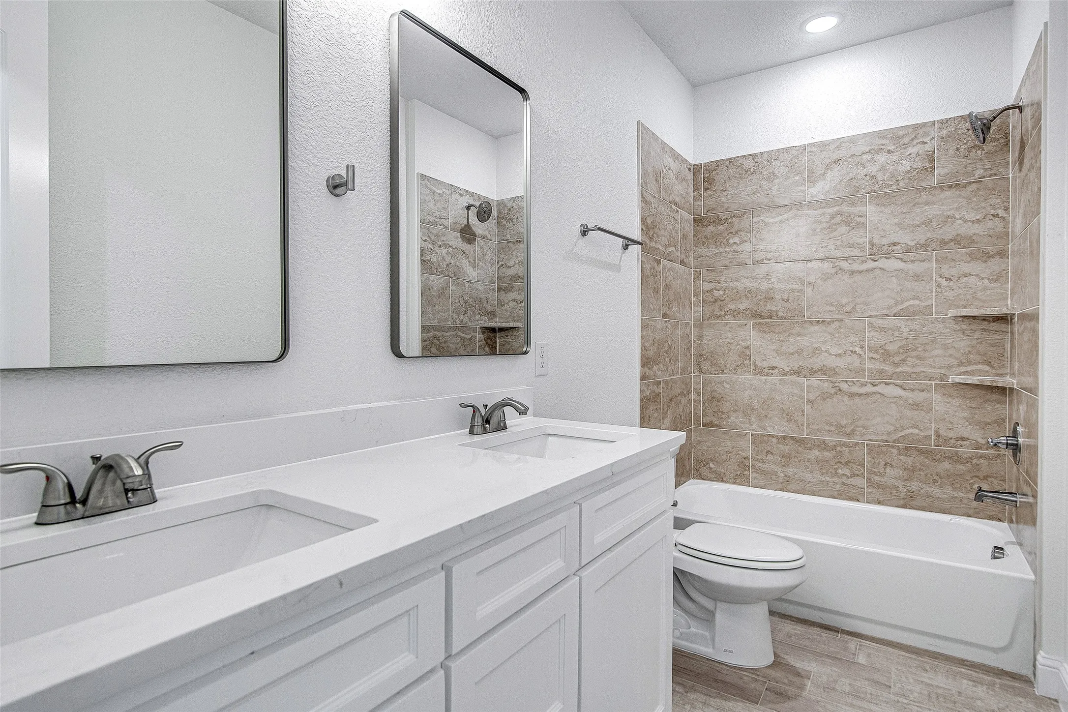 Full bathroom with wood finished floors, toilet, shower / tub combination, and double vanity