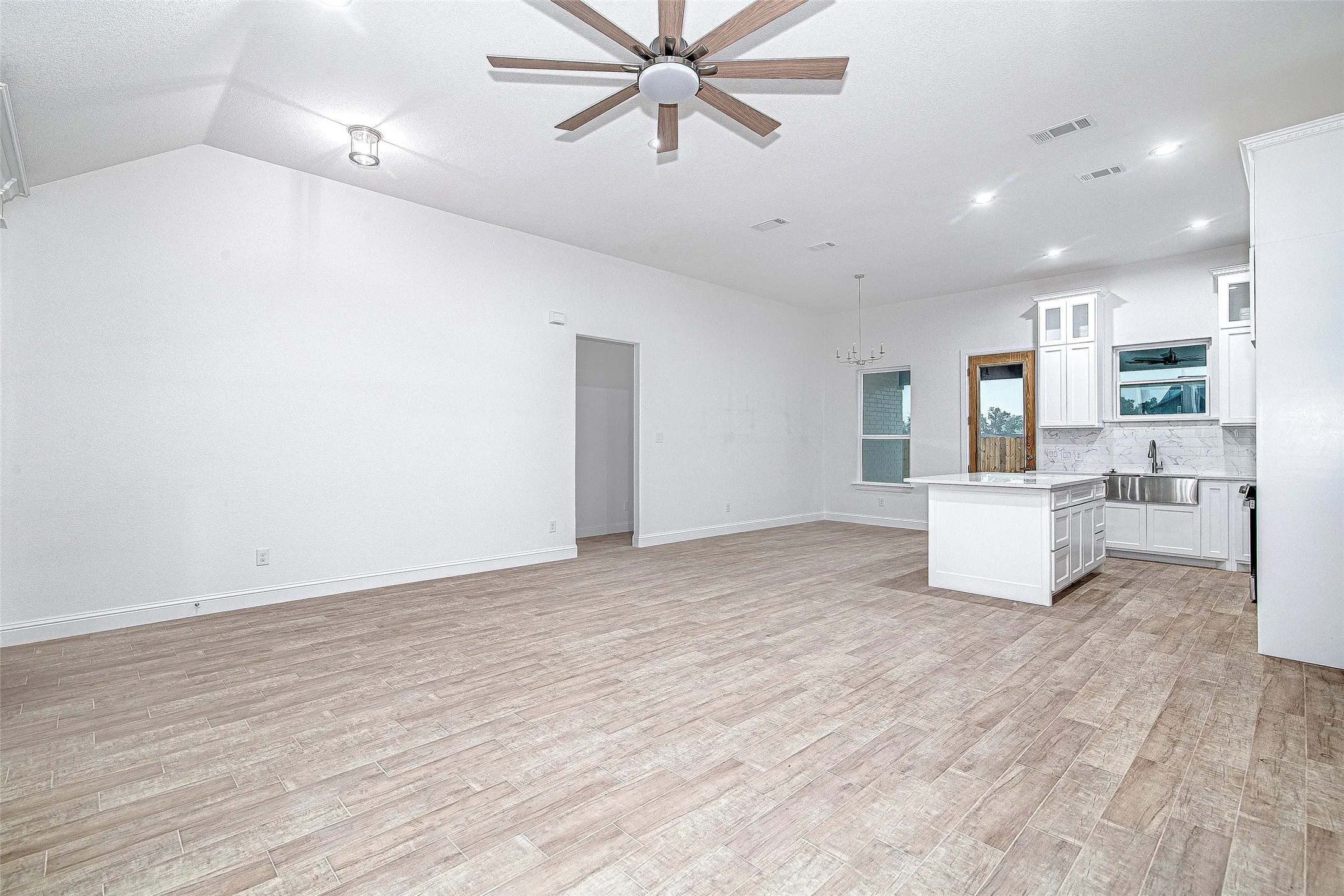 Kitchen with open floor plan, light countertops, a chandelier, a sink, and light wood finished floors