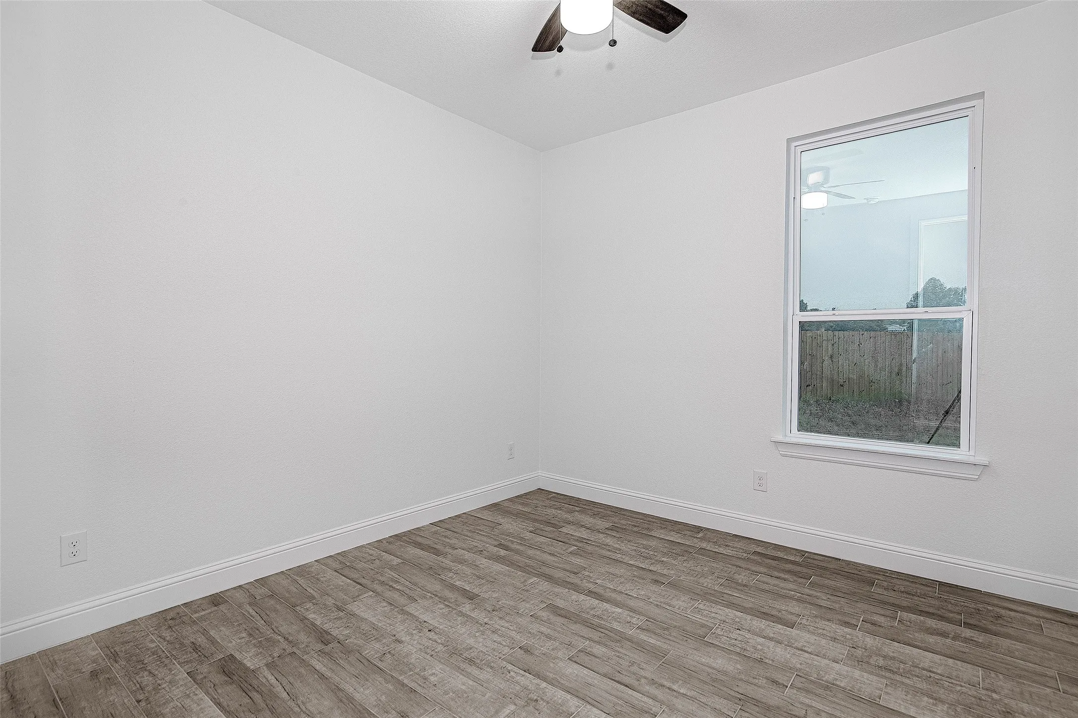 Spare room featuring a ceiling fan, wood finished floors, and baseboards