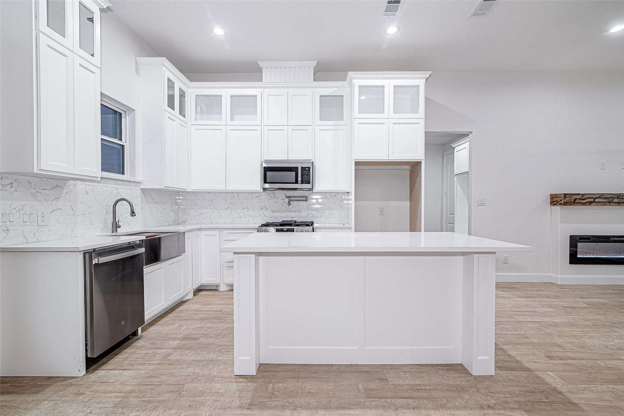 Kitchen featuring stainless steel appliances, a sink, a center island, backsplash, and light countertops