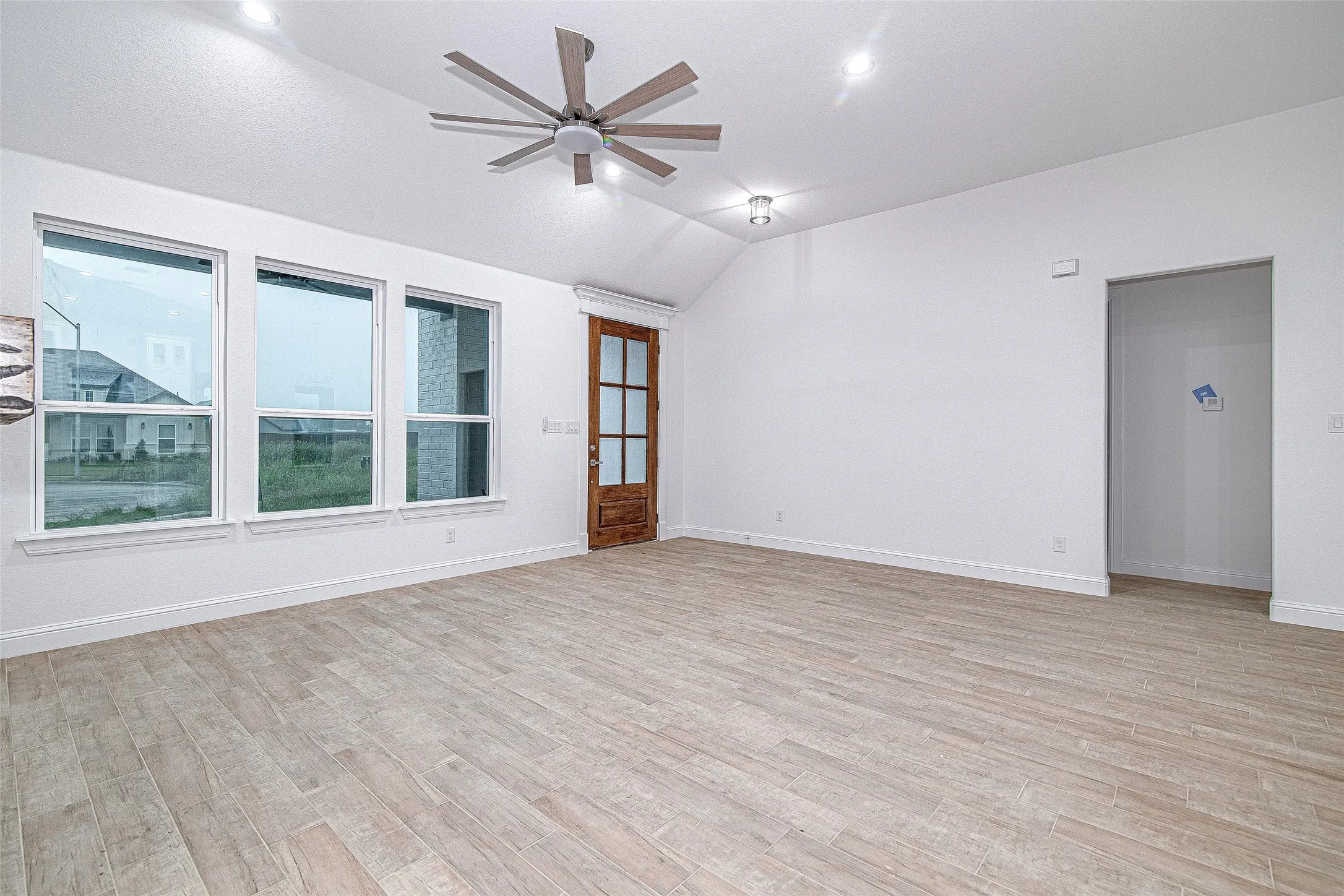 Empty room with vaulted ceiling, a ceiling fan, light wood finished floors, baseboards, and recessed lighting