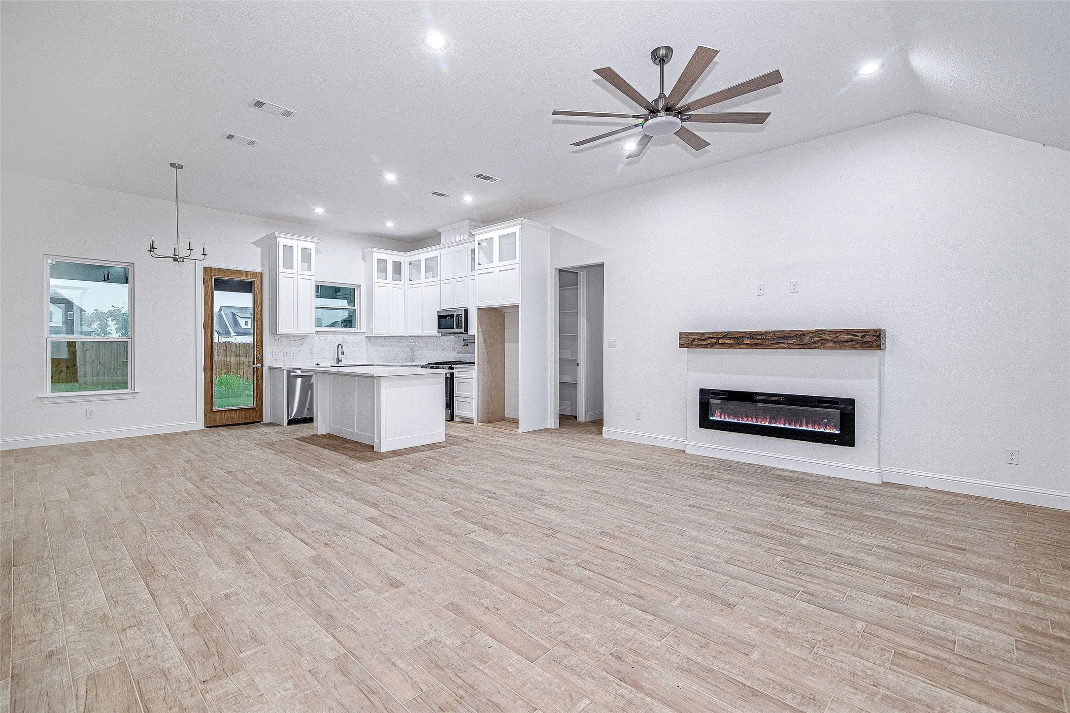 Kitchen with open floor plan, stainless steel appliances, light countertops, backsplash, and white cabinetry