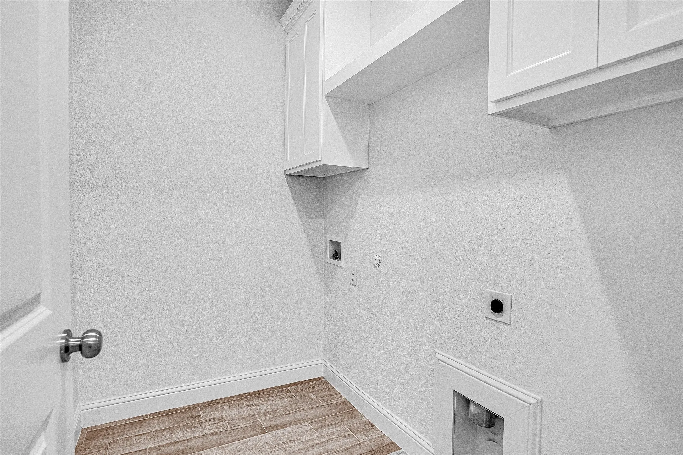Laundry area featuring cabinet space, electric dryer hookup, light wood-type flooring, baseboards, and hookup for a gas dryer