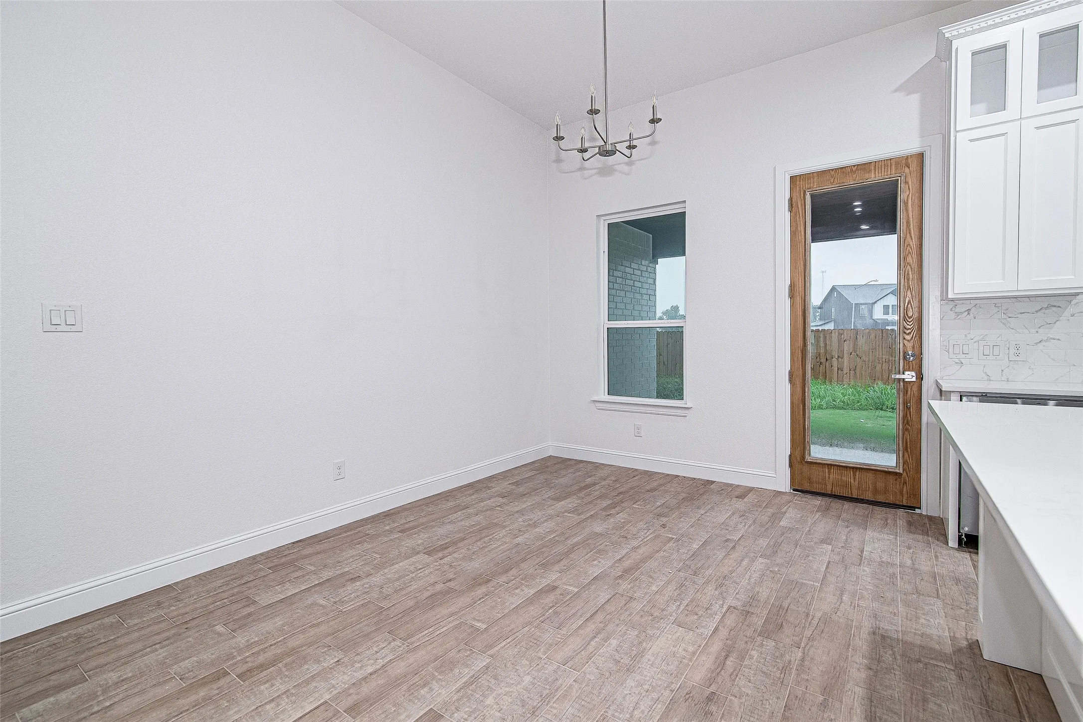 Unfurnished dining area with a chandelier, light wood finished floors, lofted ceiling, and baseboards