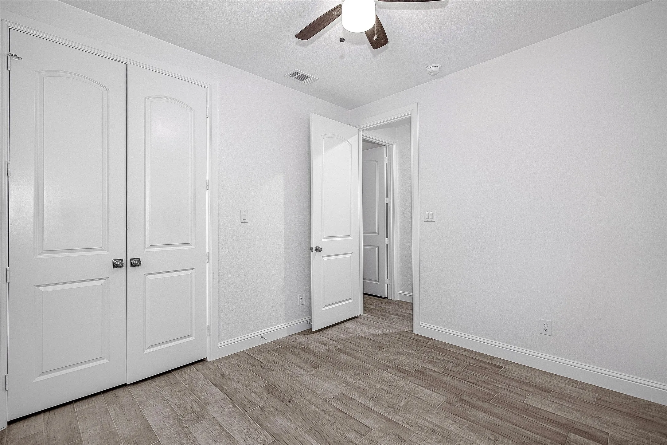 Unfurnished bedroom featuring light wood-type flooring, baseboards, a closet, and a ceiling fan