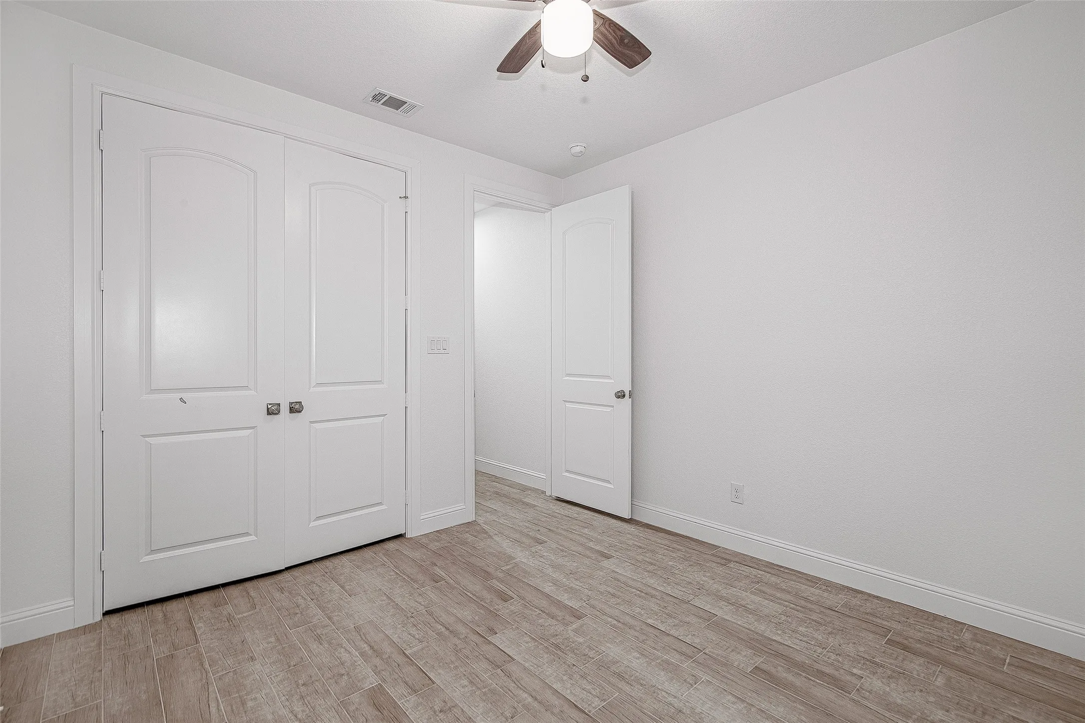 Unfurnished bedroom featuring light wood-type flooring, baseboards, a closet, and ceiling fan
