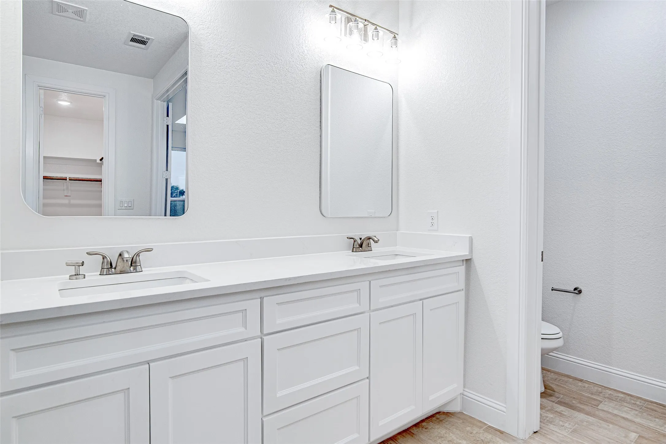 Full bathroom featuring wood finished floors, toilet, baseboards, and double vanity