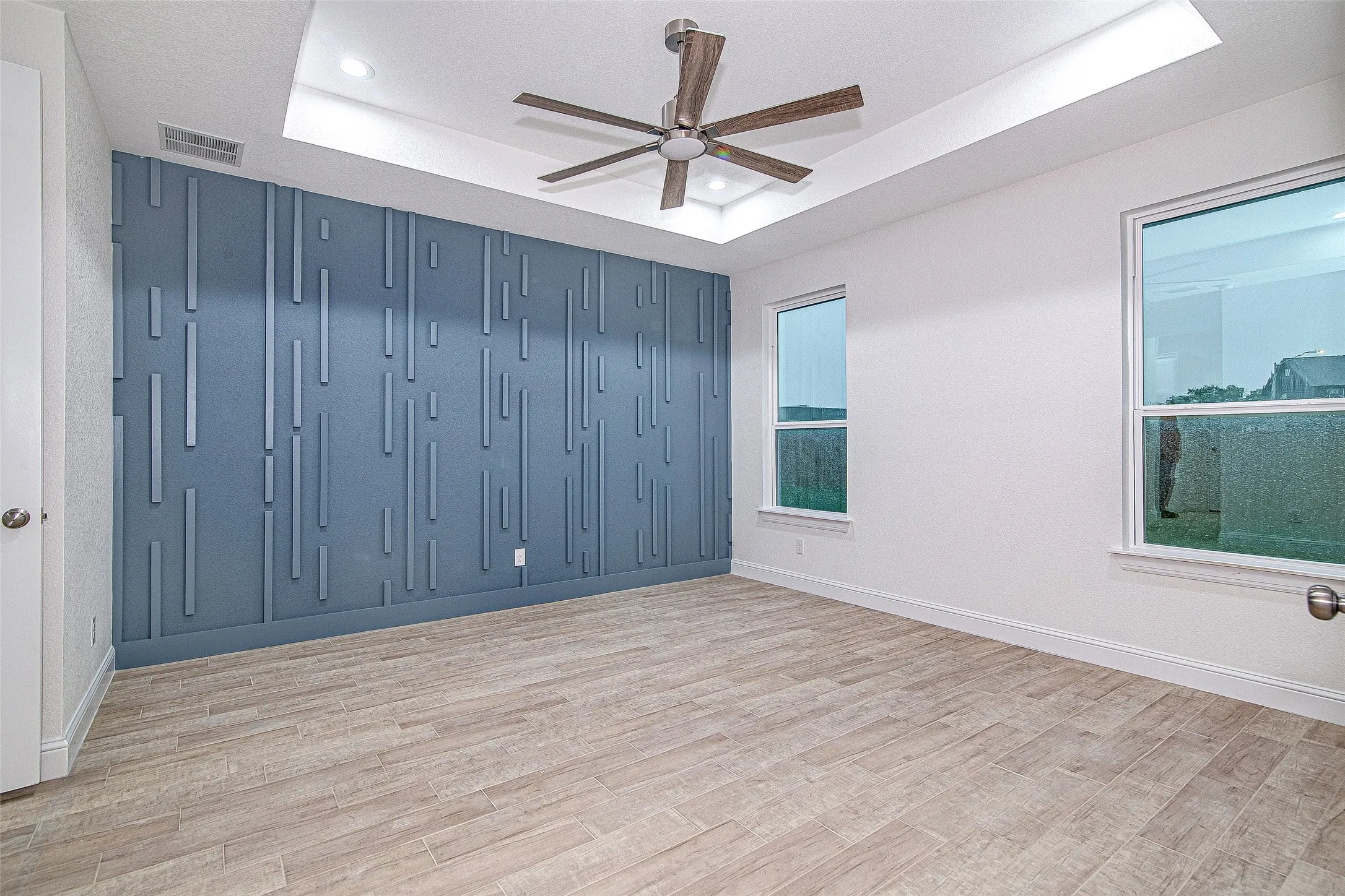 Spare room with a tray ceiling, a ceiling fan, light wood-style floors, baseboards, and recessed lighting
