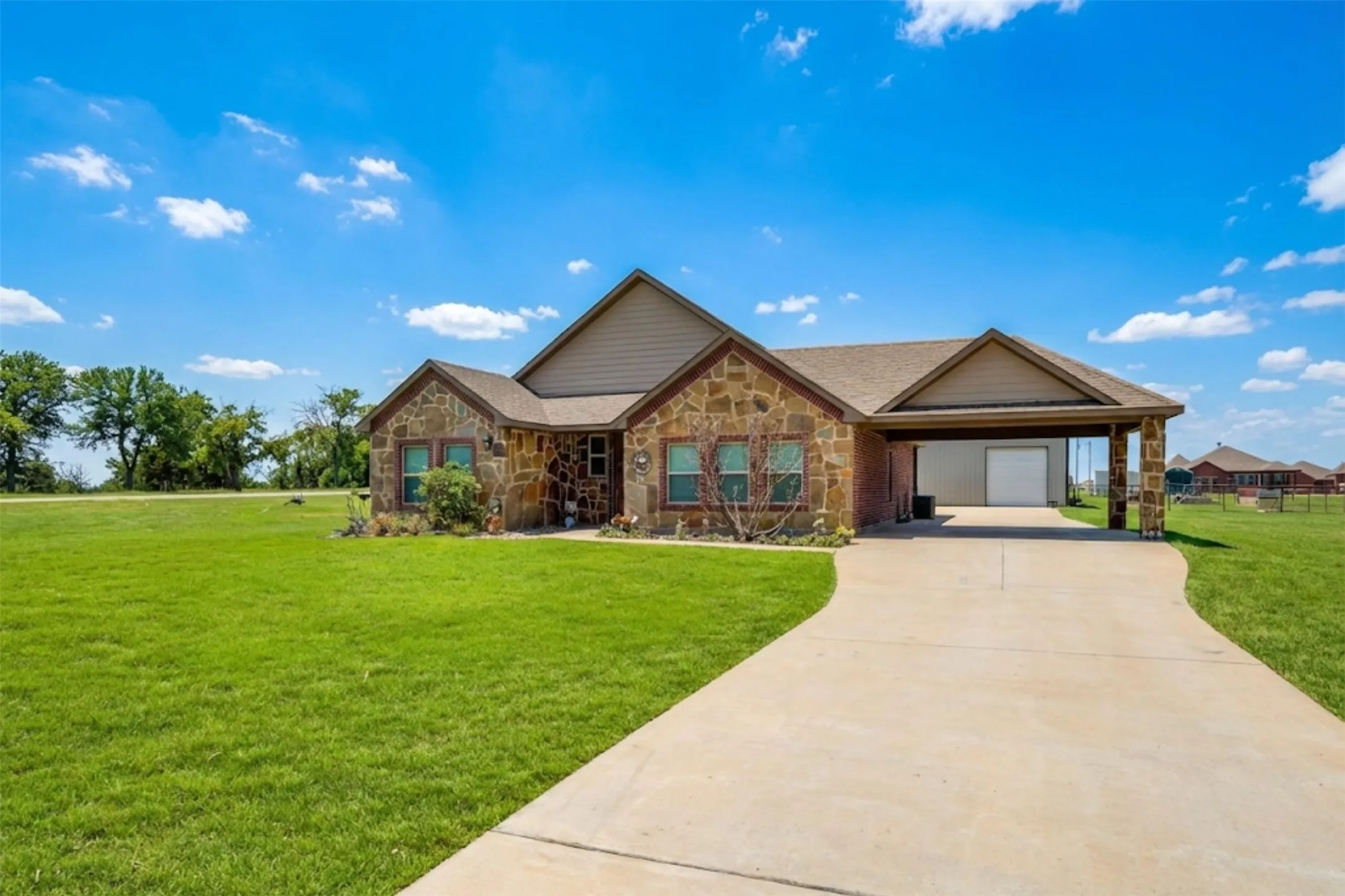 Ranch-style home with stone siding, a front lawn, an attached carport, and concrete driveway
