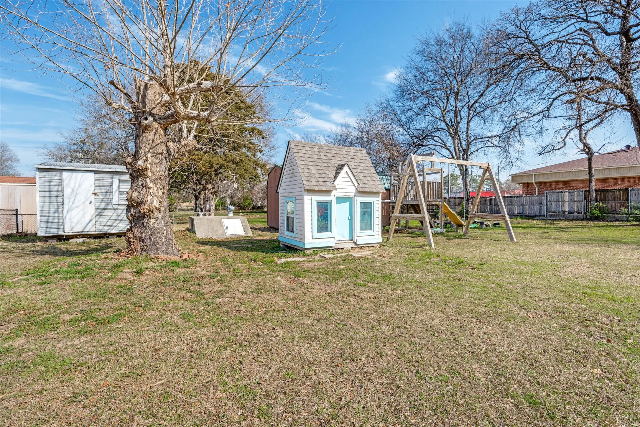 Fenced backyard with a storage shed and a playground