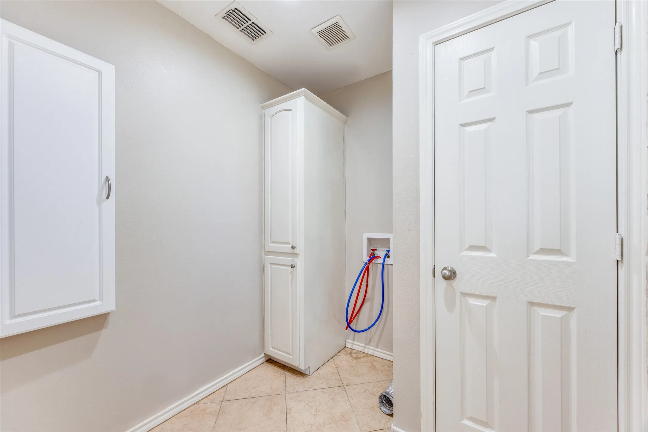 Hall with light tile patterned flooring and baseboards