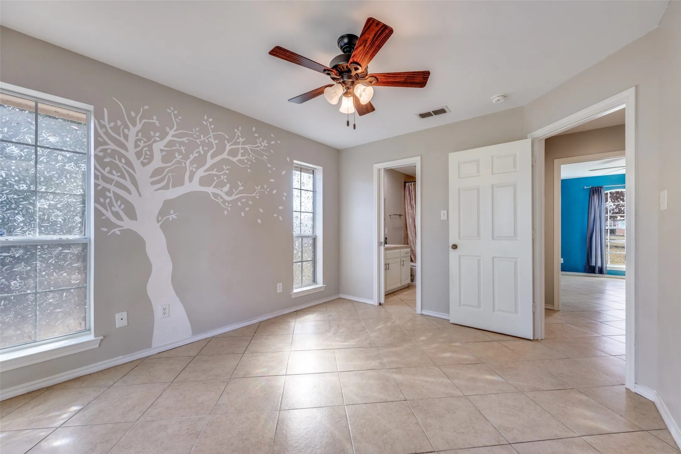 Unfurnished bedroom with ensuite bath, ceiling fan, and light tile patterned floors