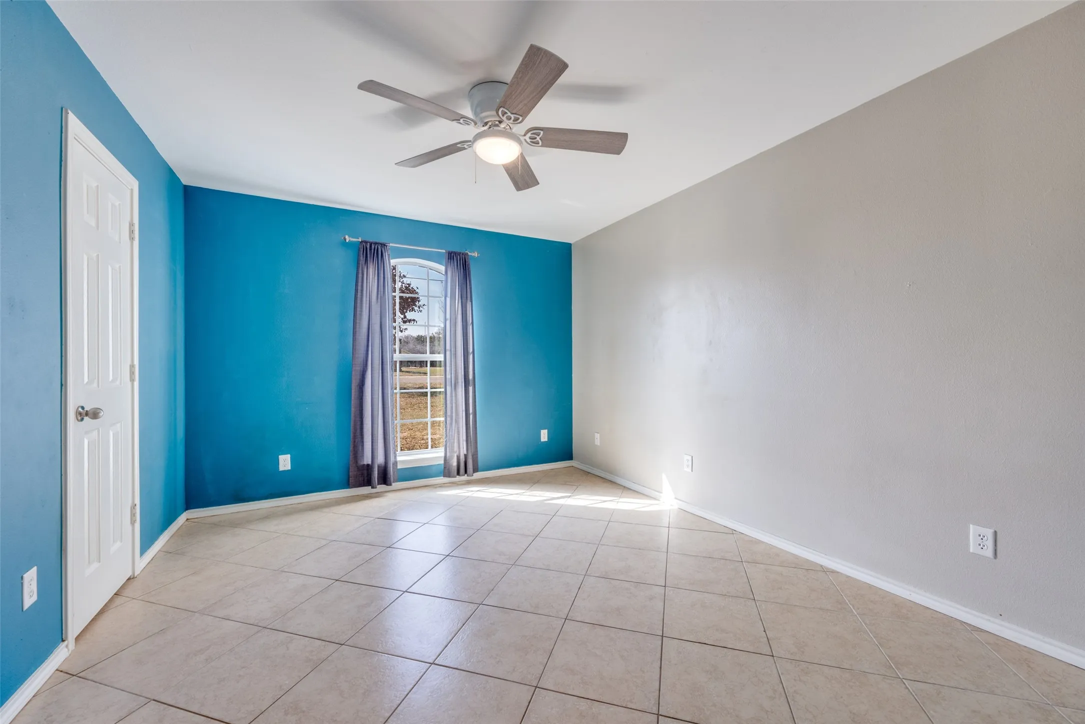 Empty room featuring ceiling fan and light tile patterned flooring