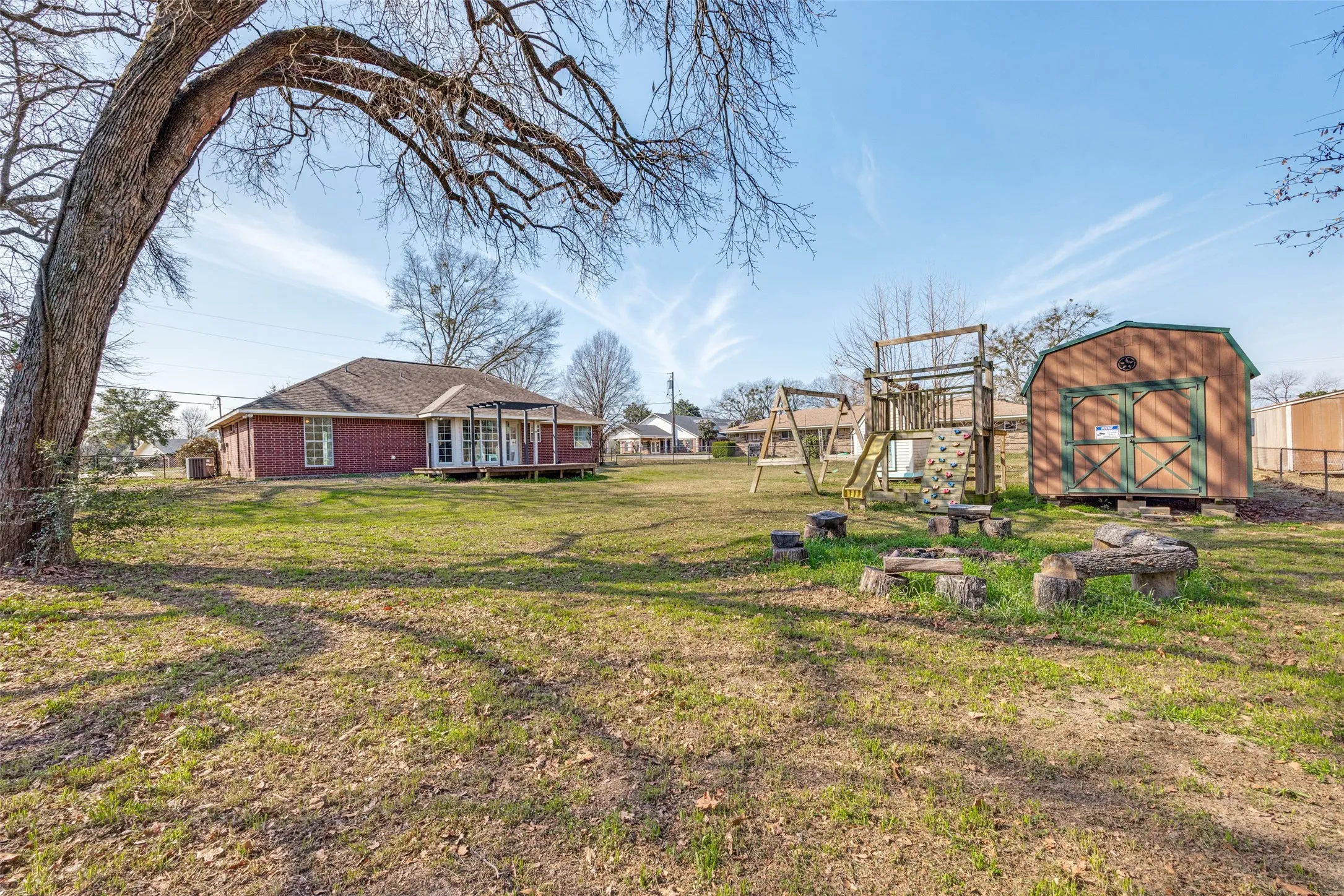 View of grassy yard featuring a storage shed and a playground