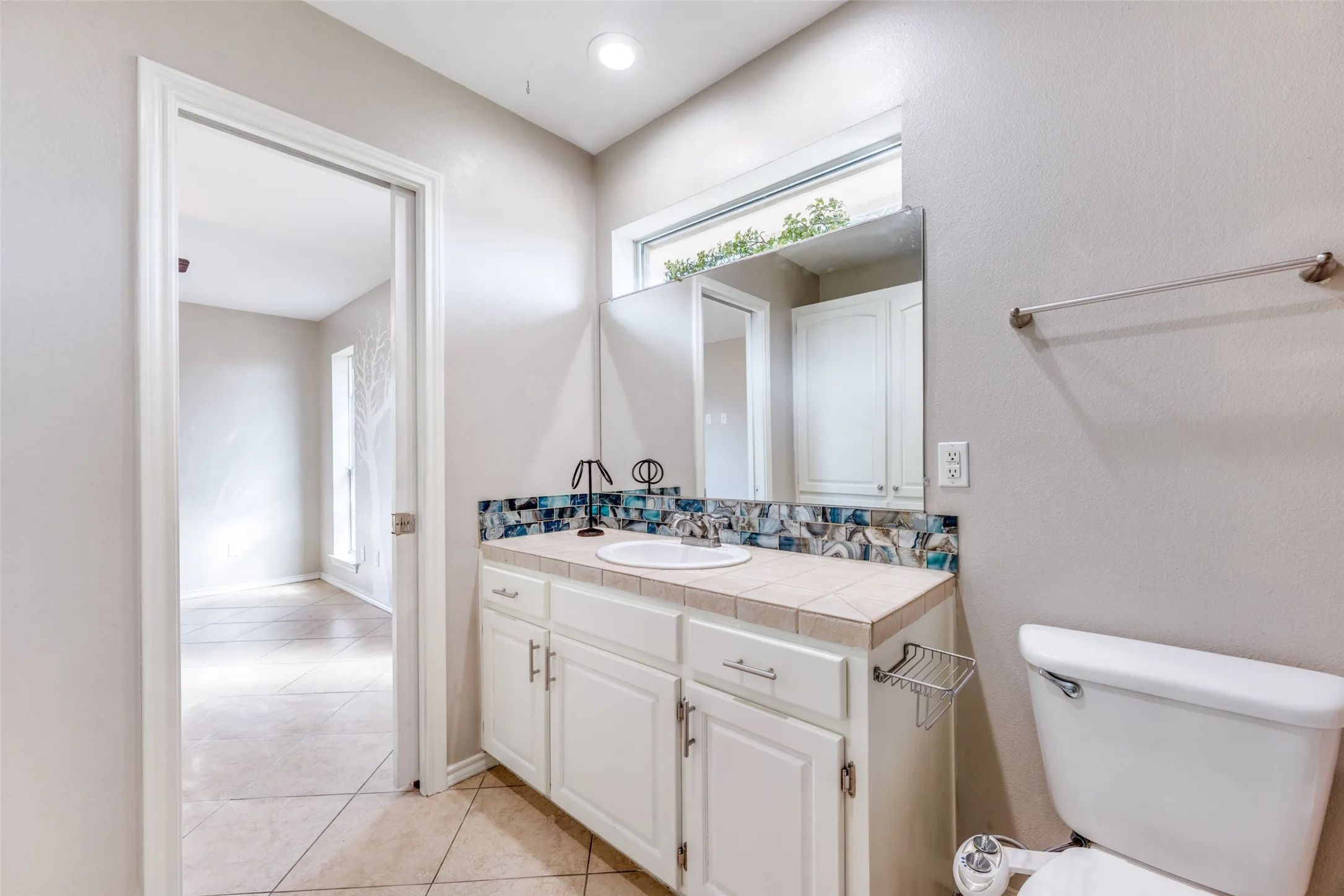 Half bathroom with vanity, light tile patterned floors, and backsplash