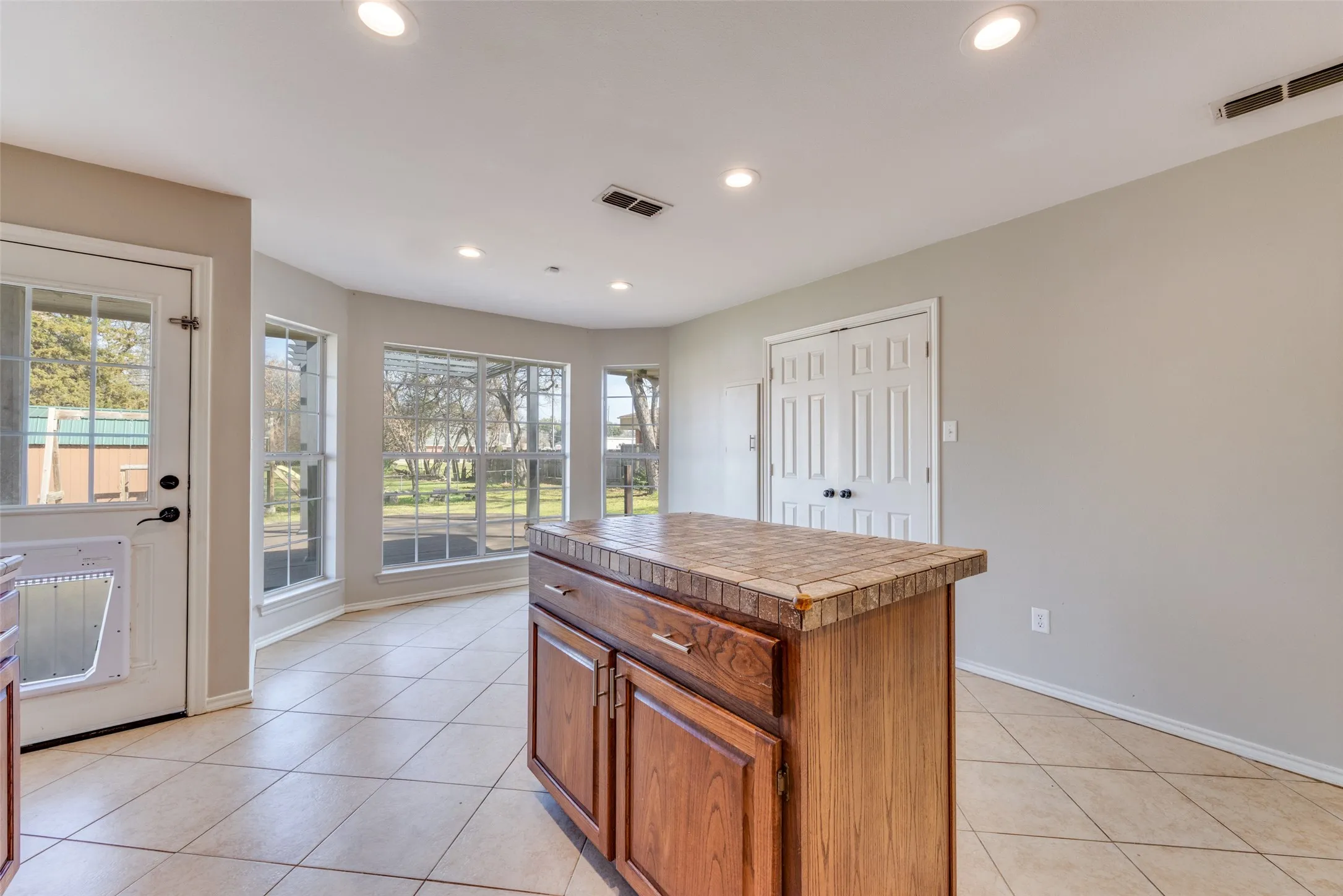 Kitchen with tile countertops, wood finish cabinetry, light tile patterned floors, a kitchen island, and recessed lighting