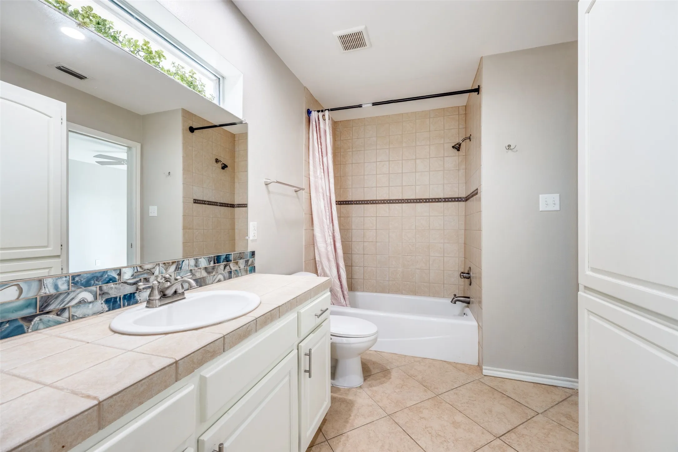 Full bath with vanity, shower / tub combo with curtain, and light tile patterned floors