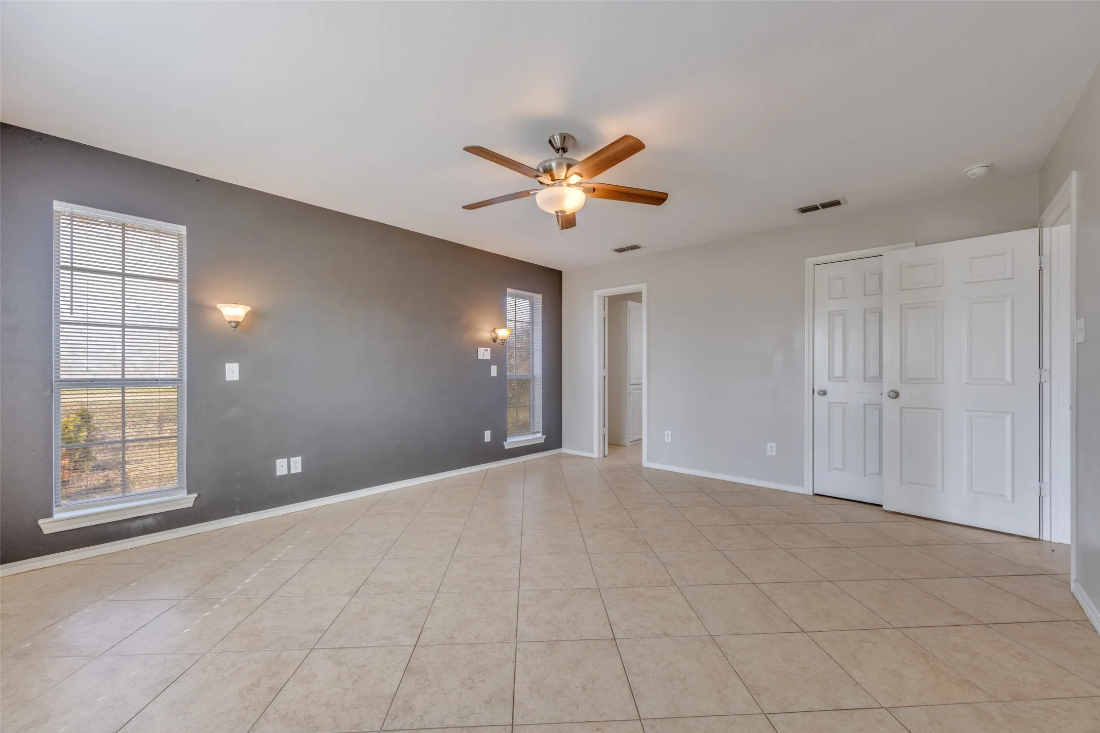 Unfurnished bedroom with a ceiling fan, light tile patterned flooring, and multiple windows