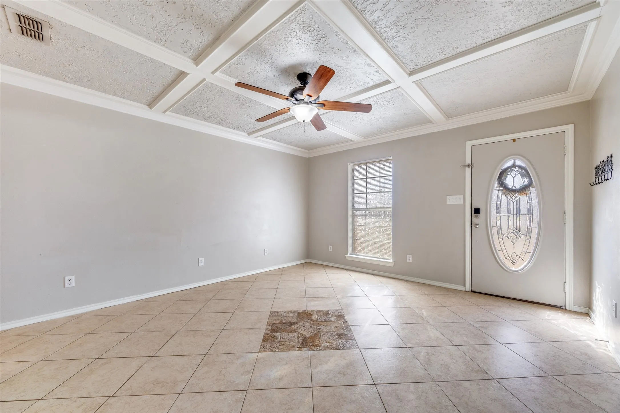 Foyer featuring coffered ceiling, ceiling fan, light tile patterned floors, and ornamental molding