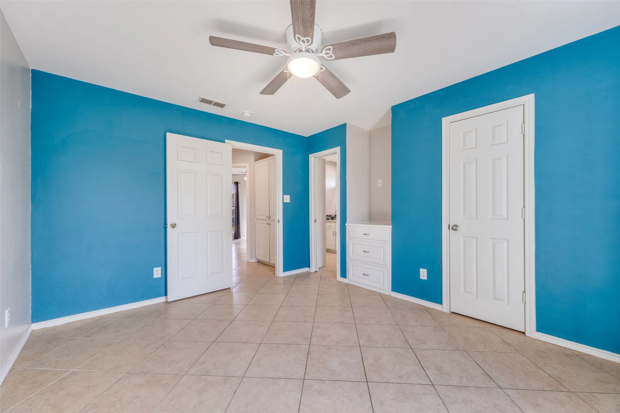 Unfurnished bedroom with a ceiling fan, light tile patterned floors, and connected bathroom