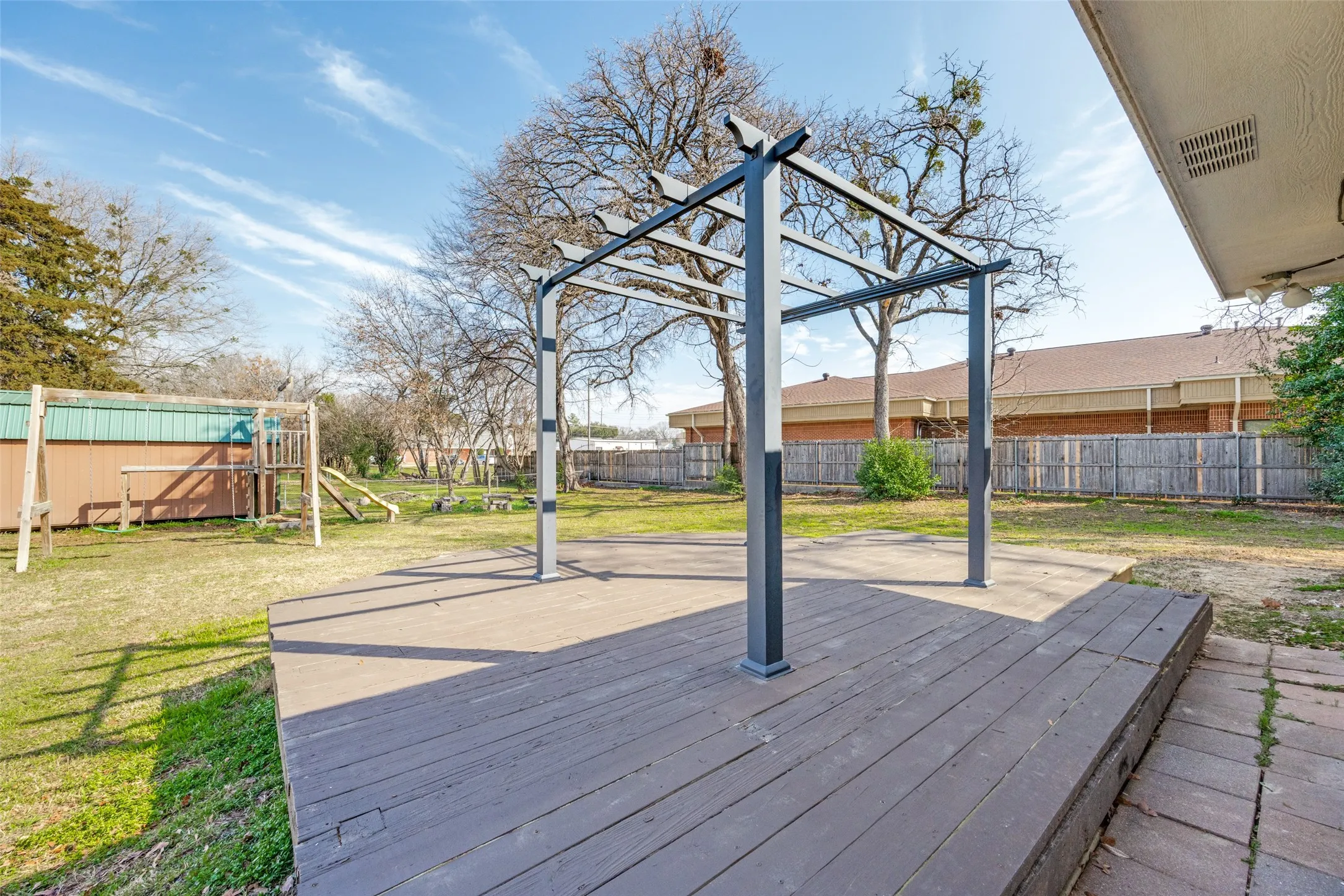 Wooden deck featuring a playground and a fenced backyard
