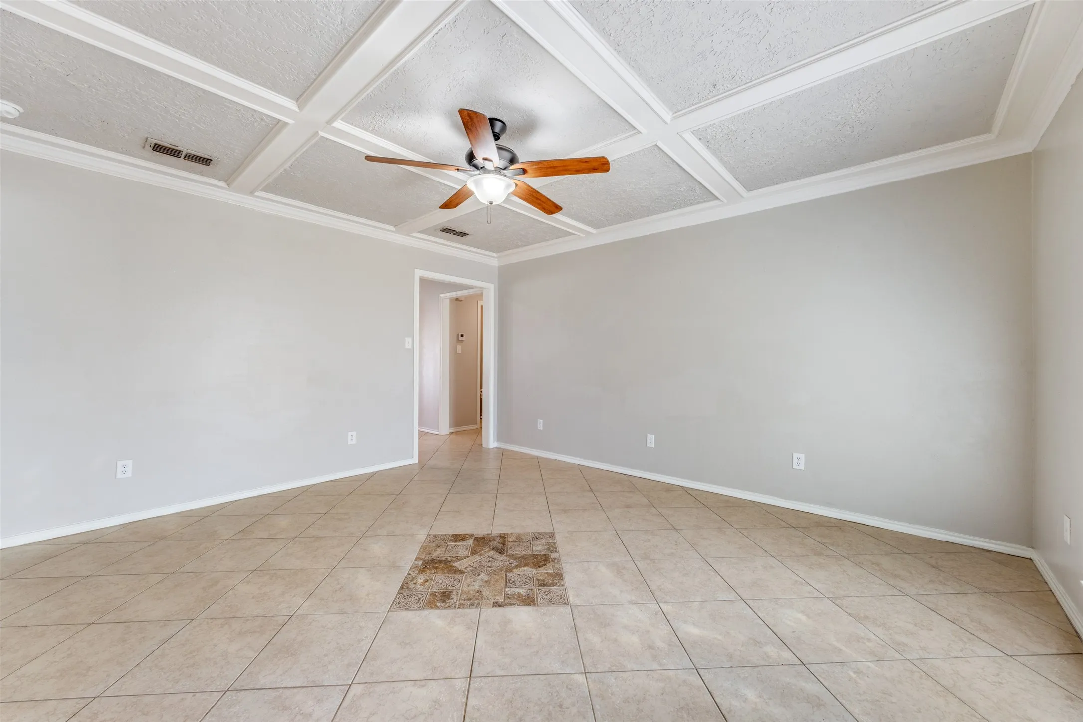 Unfurnished room featuring coffered ceiling, ceiling fan, crown molding, light tile patterned flooring, and a textured ceiling