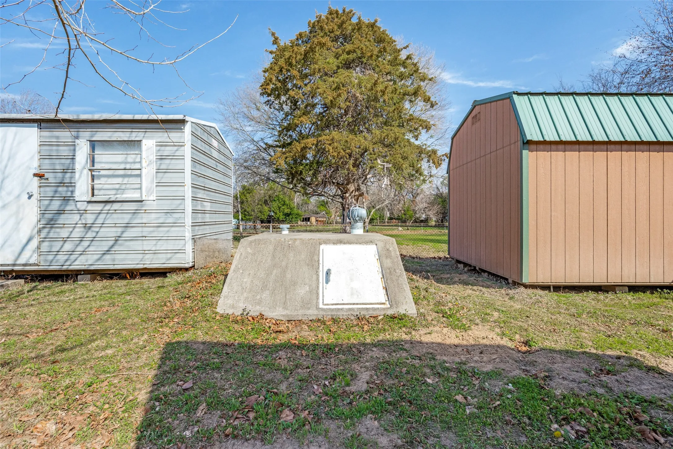 View of storm shelter featuring a storage shed and a lawn