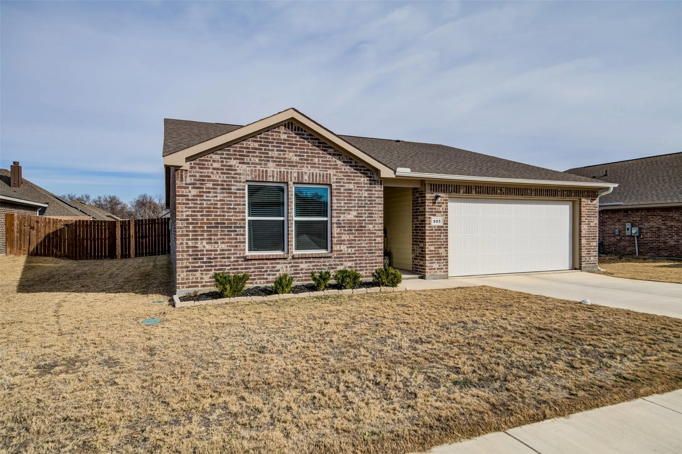 Ranch-style house with roof with shingles, driveway, brick siding, and a garage