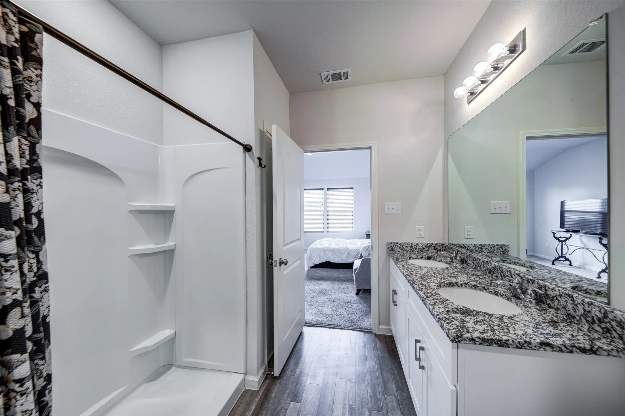 Bathroom featuring double vanity, ensuite bath, dark wood-type flooring, and curtained shower