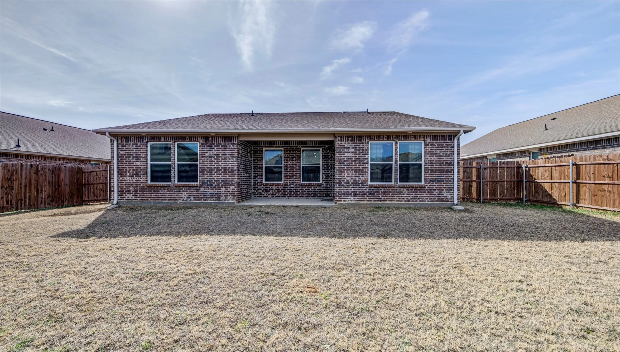 Back of property featuring a patio area, brick siding, a fenced backyard, and roof with shingles