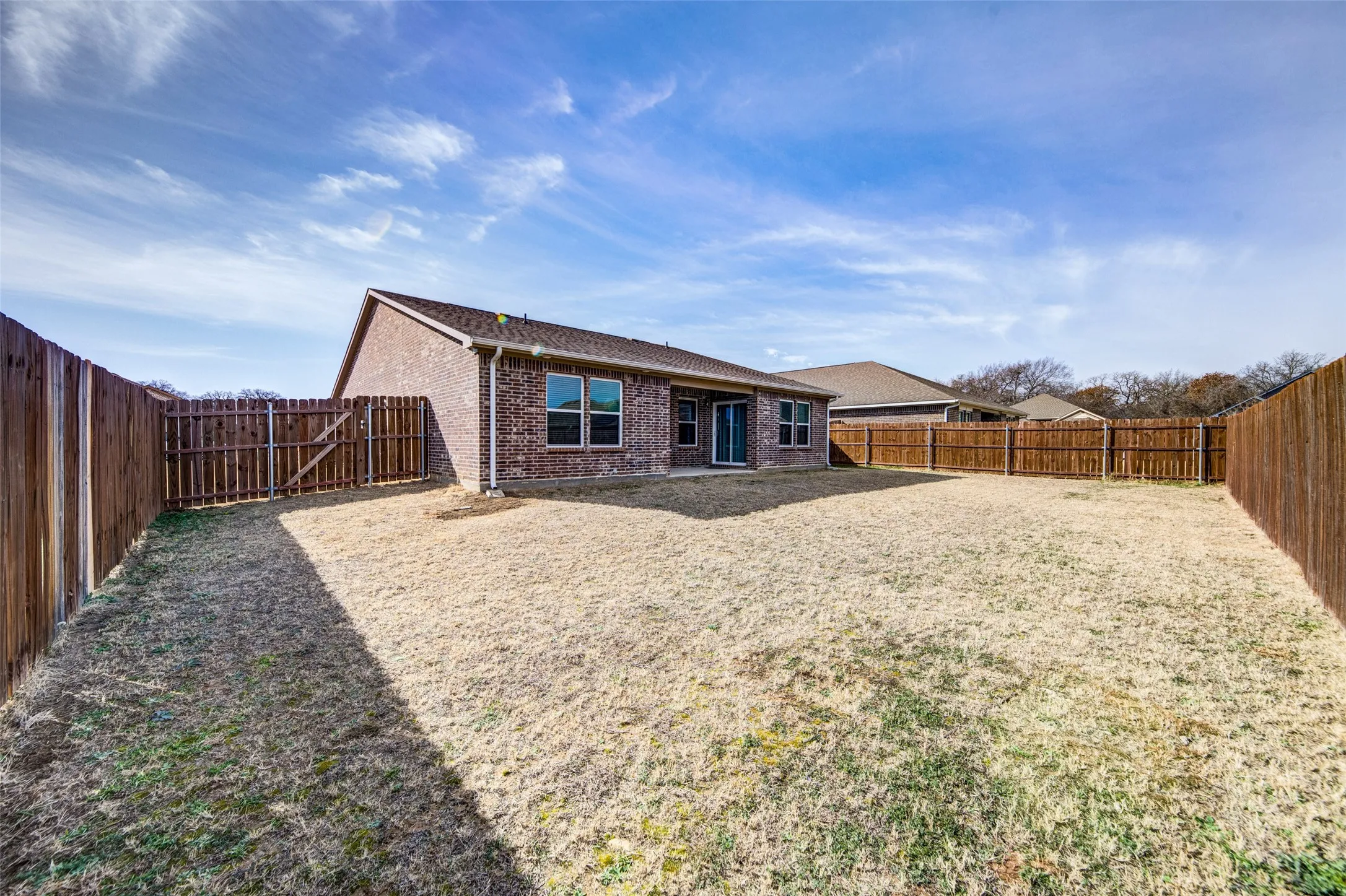 Rear view of house with brick siding, a patio, and a fenced backyard