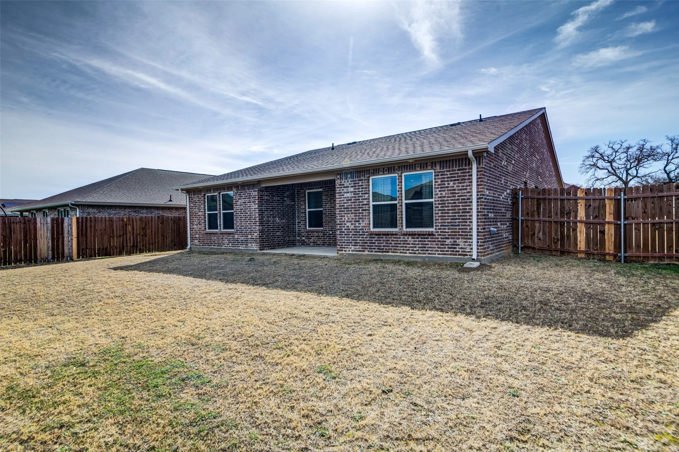 Back of property with a patio area, brick siding, a shingled roof, and a fenced backyard