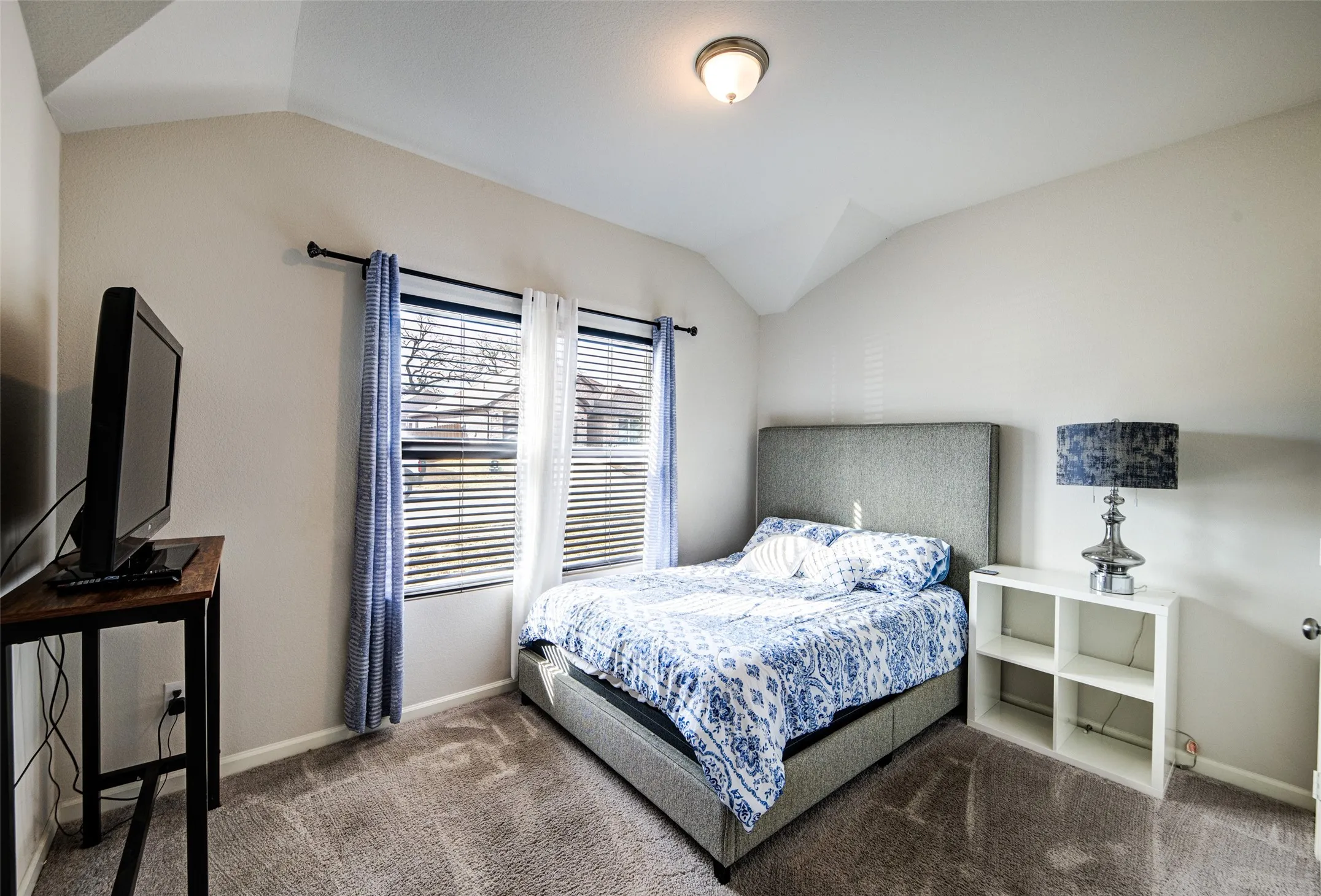 Carpeted bedroom featuring vaulted ceiling and baseboards