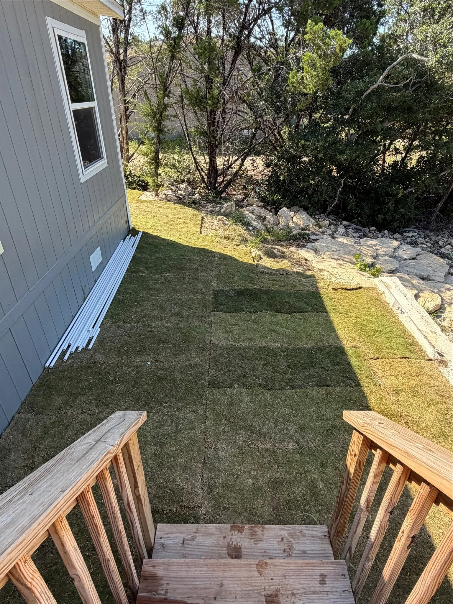 Wood steps with railings descending to a sodded lawn area
