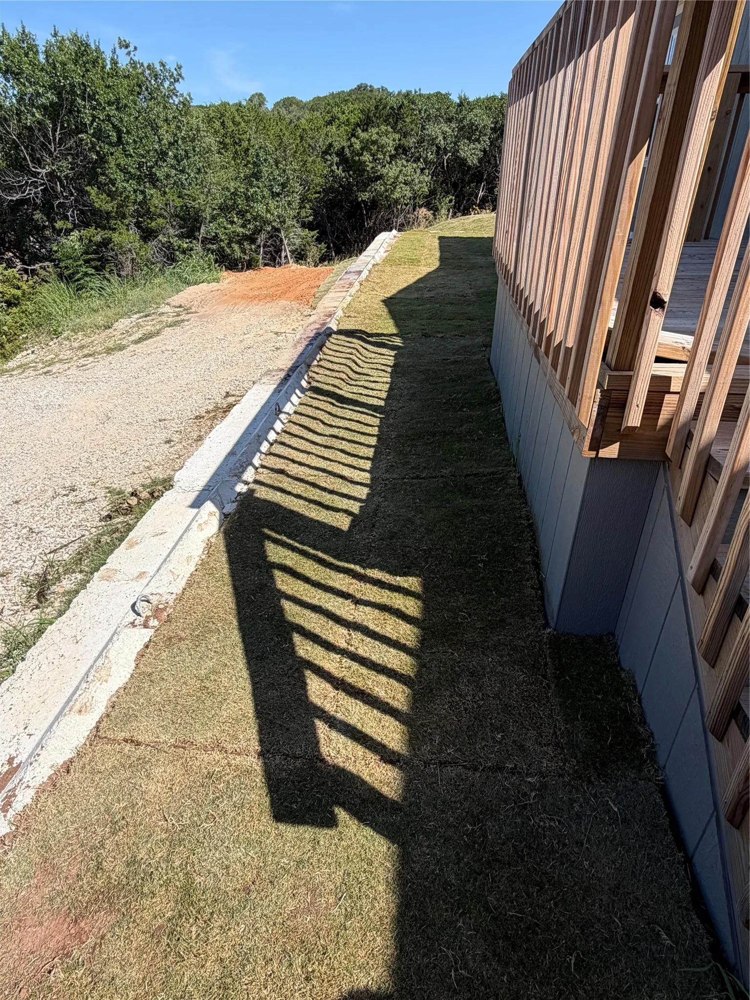 Manicured lawn area alongside a retaining wall and natural wood railing