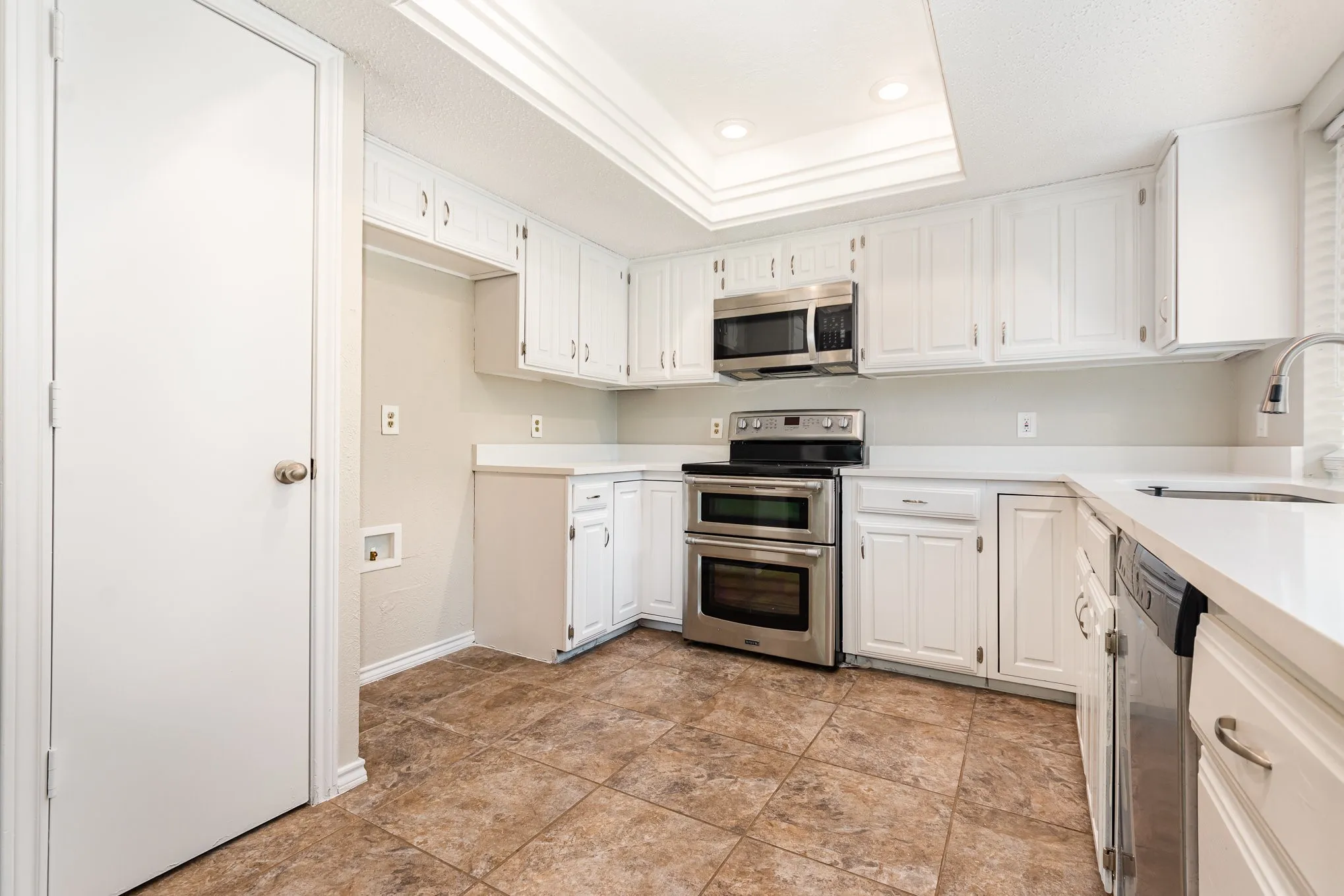 Kitchen featuring appliances with stainless steel finishes, white cabinets, and recessed lighting