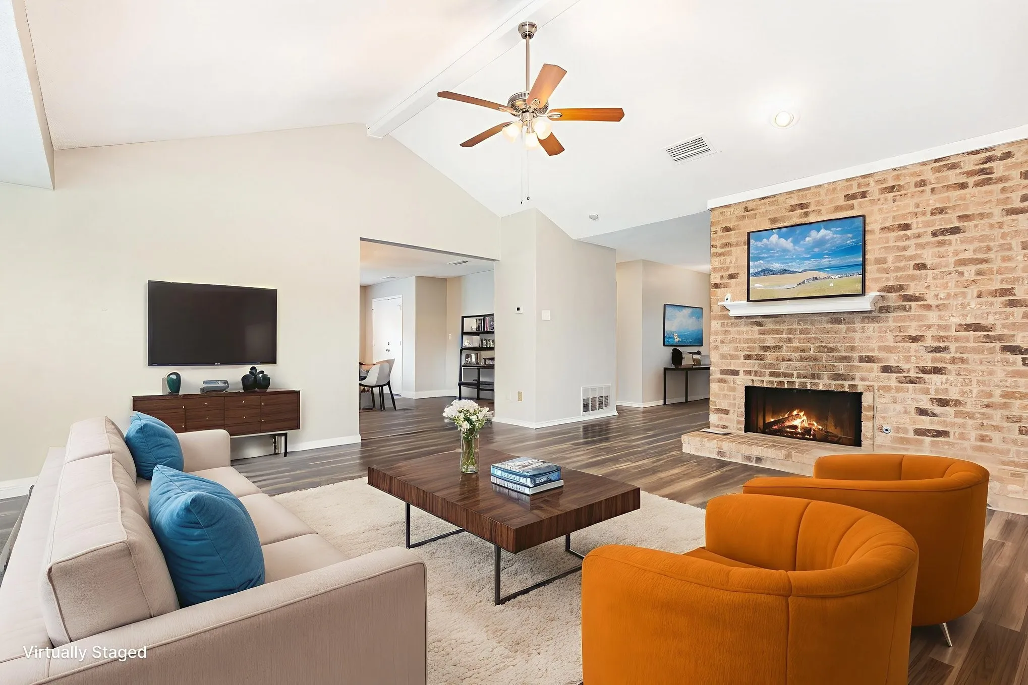 Virtually staged.Living area with beam ceiling, wood finished floors, a ceiling fan, a fireplace, and high vaulted ceiling
