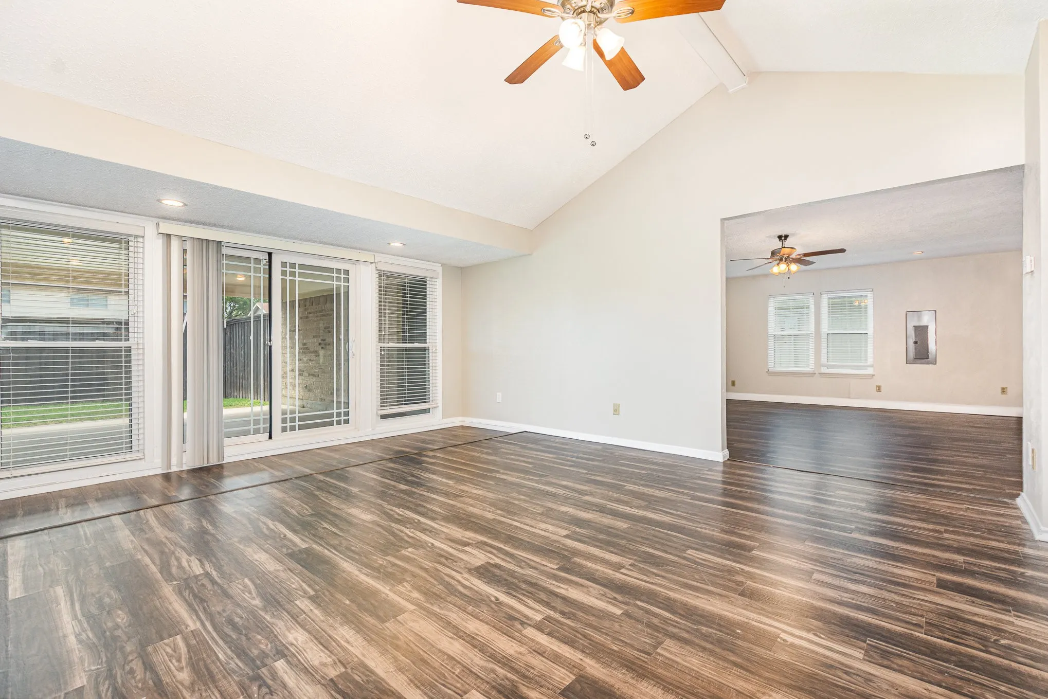 Empty room featuring ceiling fan, wood finished floors, beamed ceiling, and high vaulted ceiling