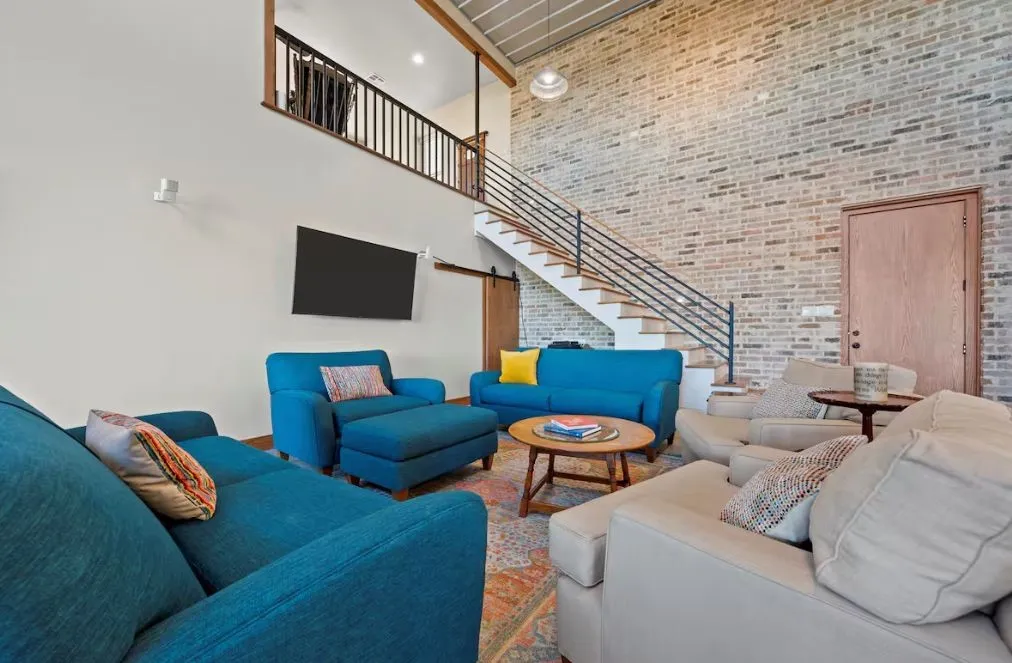 Living room featuring a high ceiling, brick wall, and stairway