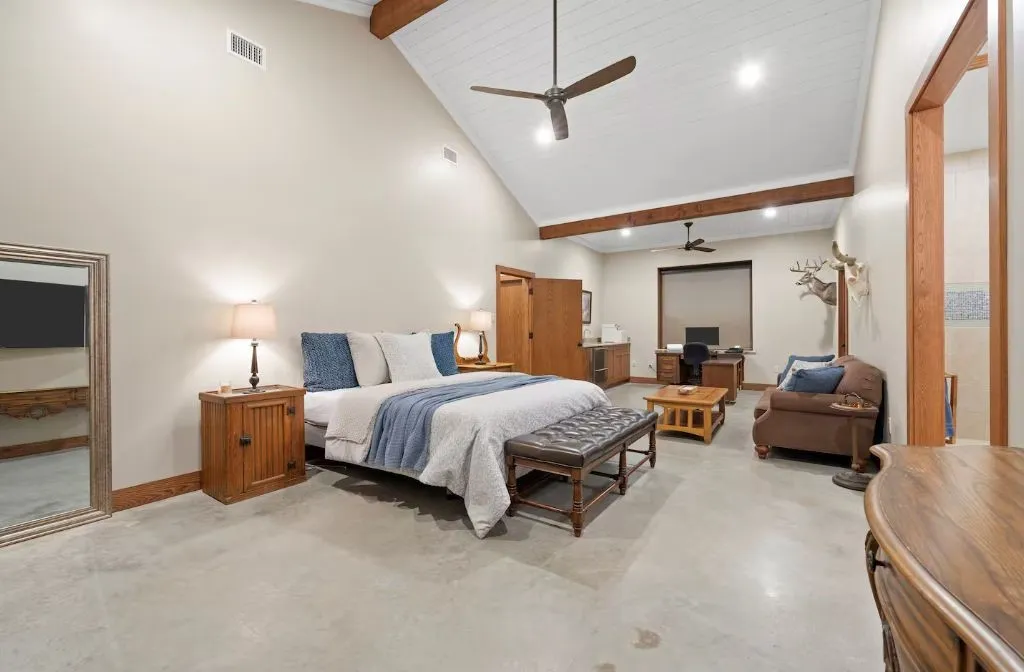Bedroom with beamed ceiling, high vaulted ceiling, ceiling fan, finished concrete floors, and recessed lighting