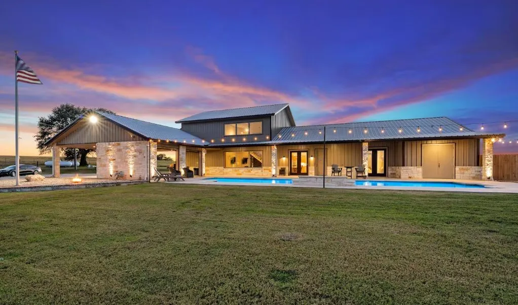 Rear view of property with a patio area, board and batten siding, a lawn, an outdoor pool, and a metal roof