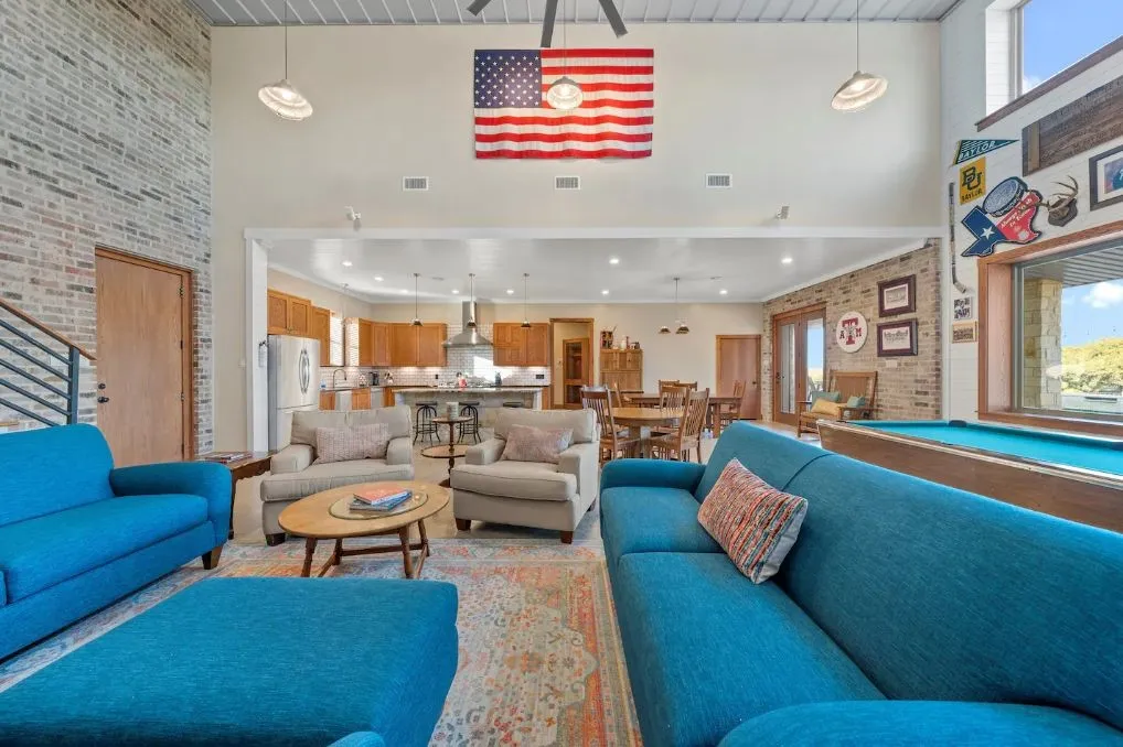 Living area with brick wall, a high ceiling, pool table, and an accent wall